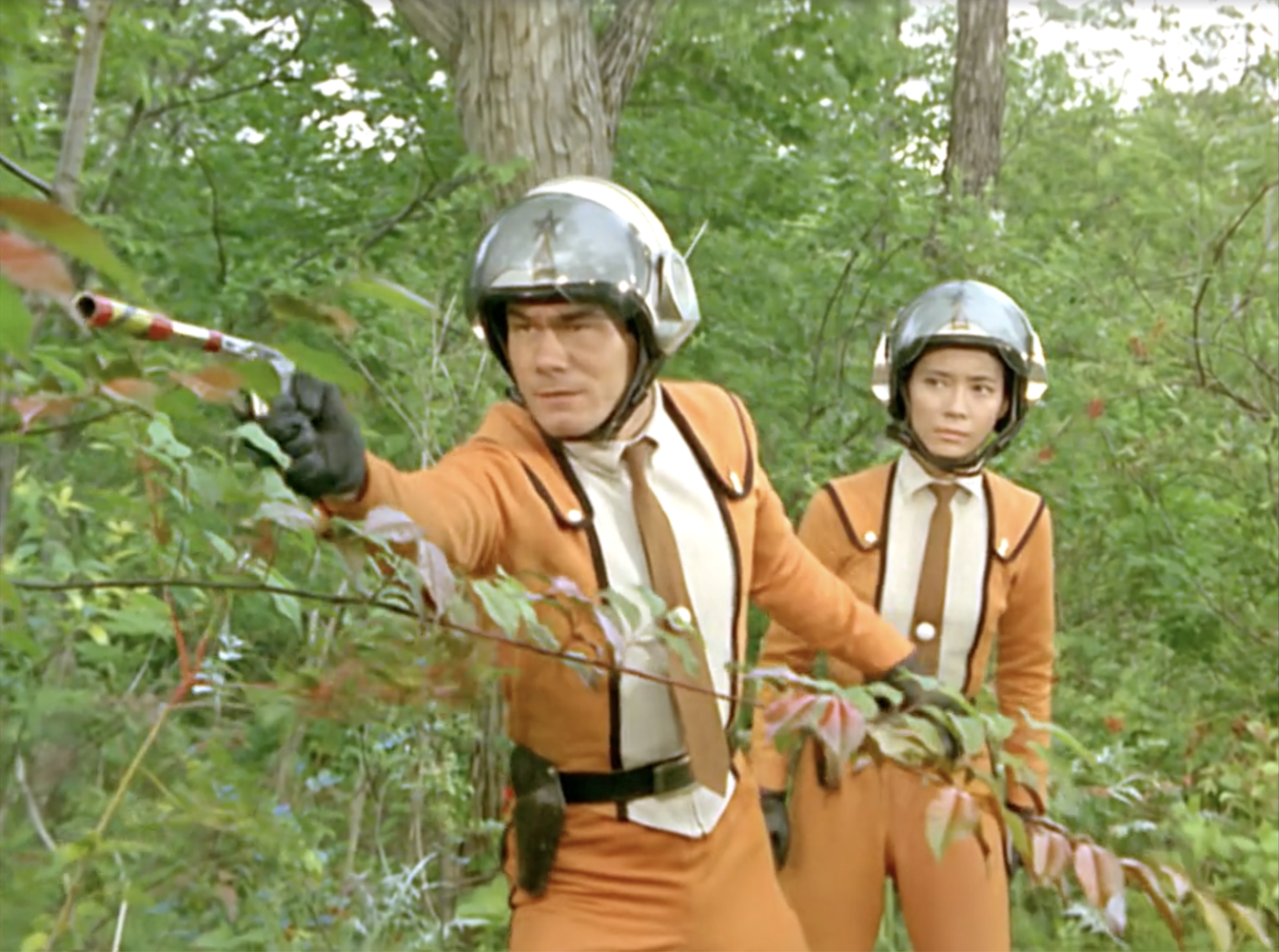 Ide with a gun and Fuji in The Monster Anarchy Zone episode of Ultraman